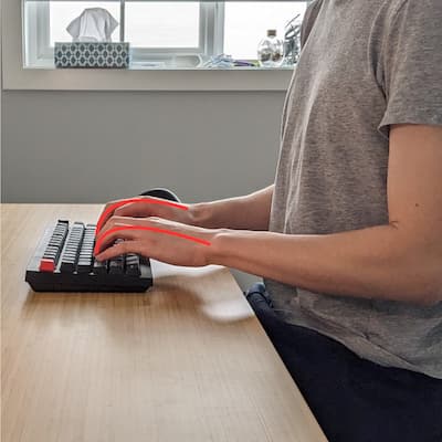 A close-up of a hand on a flat keyboard, fingers curled in a claw-like position.