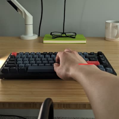 A hand on a traditional flat keyboard showing increased wrist pronation.